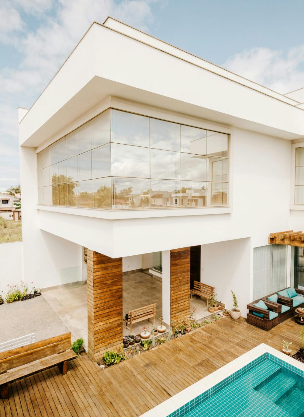 Elegant luxury home exterior featuring glass facade, wooden accents, and a swimming pool in a modern setting.